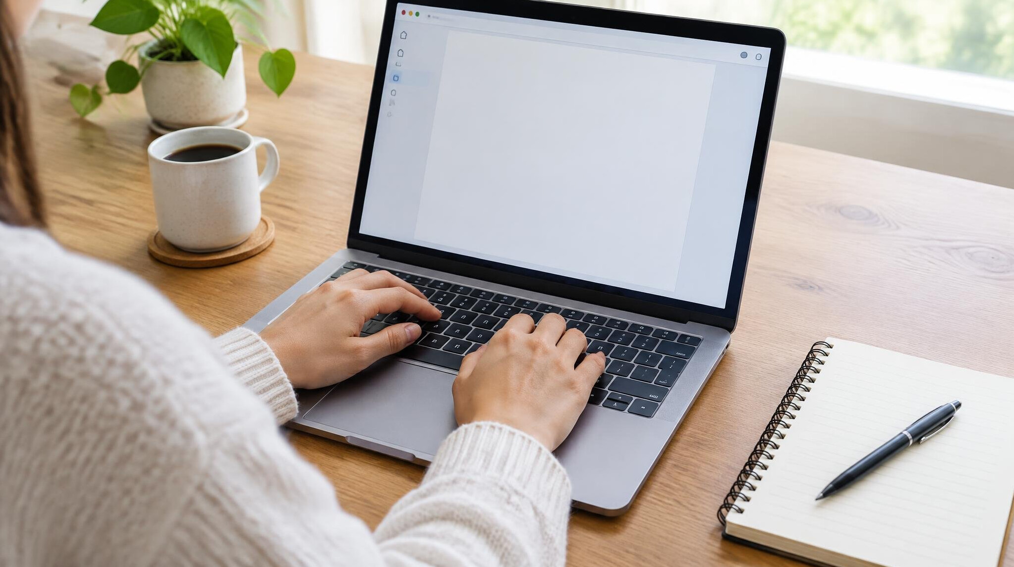 Hands typing on a laptop at a desk